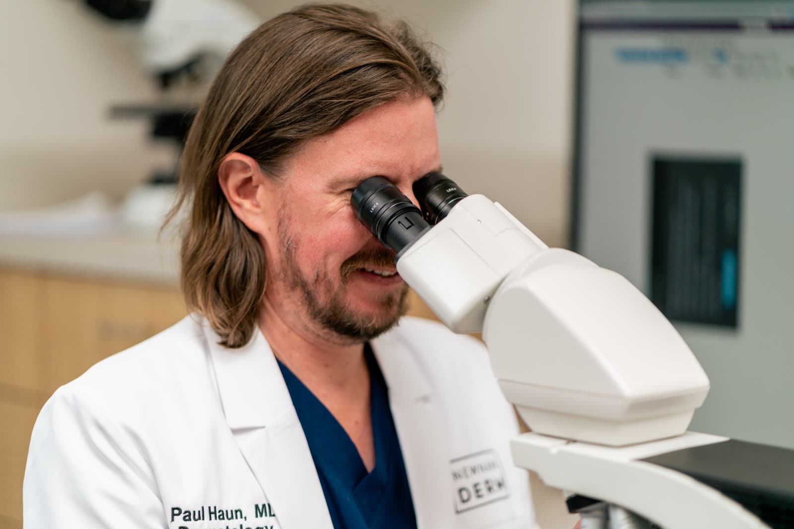 Paul Haun, MD reading pathology slides at the microscope in the Peachtree City Dermatology lab